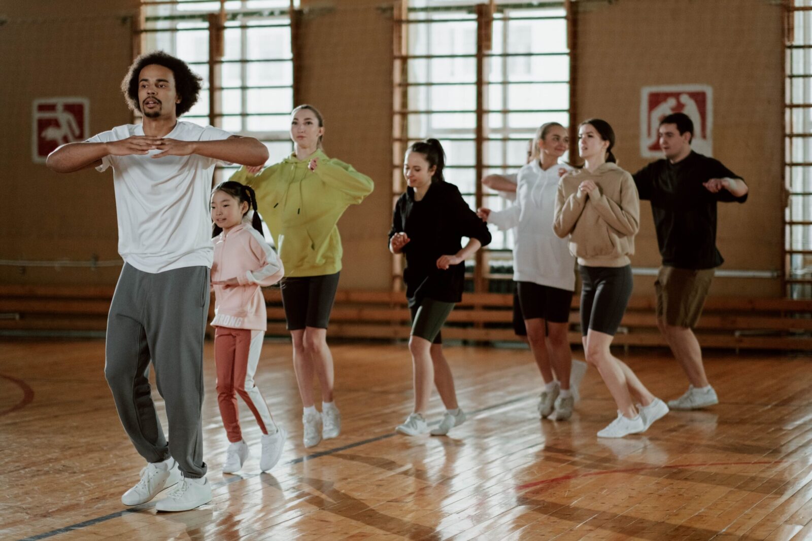 A diverse group engages in an energetic indoor fitness class focusing on exercise and coordination.
